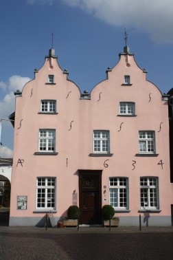 Rosafarbene Fassade des Haus Püllen vor blauem Himmel