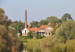 Das alte Wasserwerk der Stadt Wesel. Es handelt sich um einen Backsteinbau mit roten Dachziegeln und einem hohen Schornstein, der am Ufer der Lippe liegt.