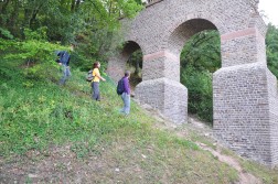 Drei Wanderer am Hang entlang laufend, vor einem alten römischen Aquädukt (Wasserleitung).
