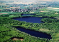 Luftbild von drei Villeseen, die von Wald umgeben sind. Im Hintergrund liegen mehrere kleinere Ortschaften.